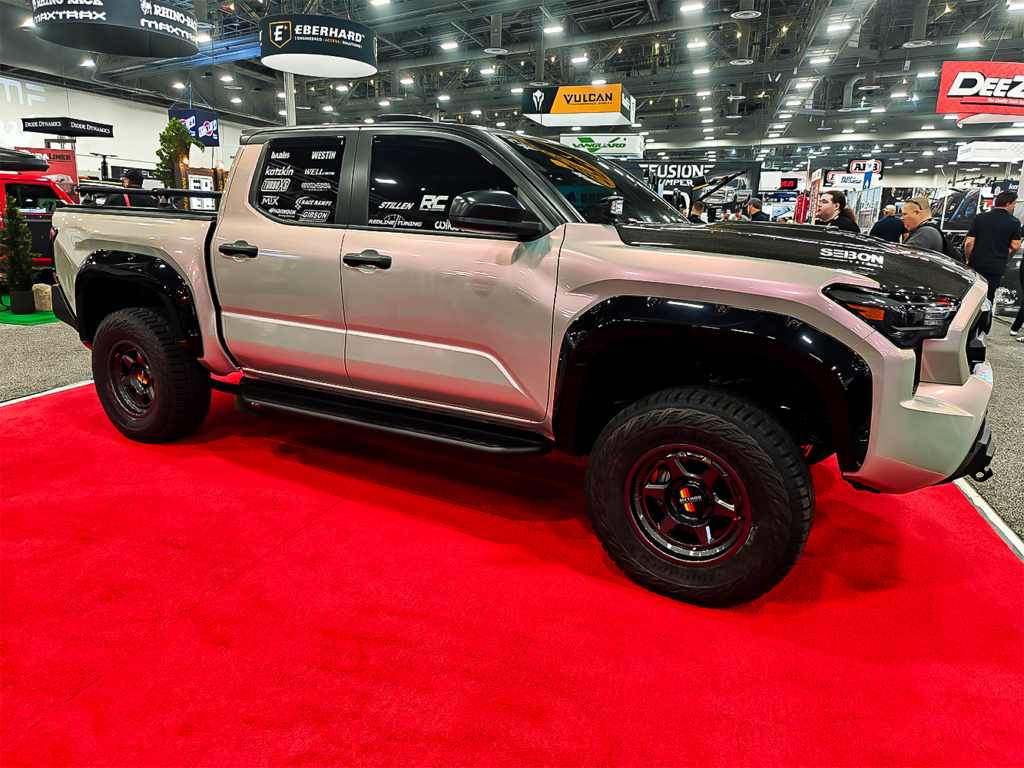 SEMA 2024 showcase featuring STILLEN's top picks: custom Nissan Z, Nissan Frontier Tarmac Edition, Infiniti QX80, Toyota Tacoma builds with Icon Vehicle Dynamics suspension, TruControl tuner, and TruPower intake, and Toyota's concept off-roaders including TRD Surf and Land Cruiser Rox